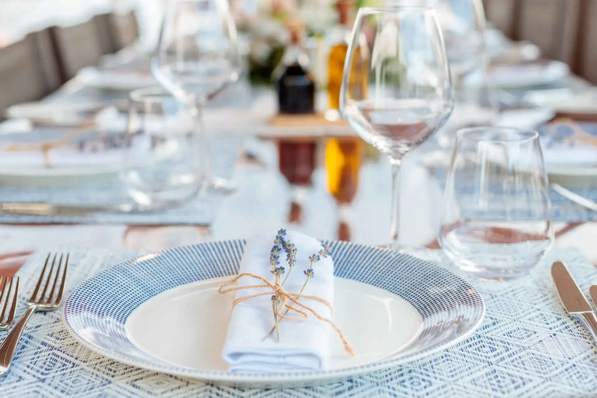 A holiday table setting with white and blue plates, folded napkins and wine glasses